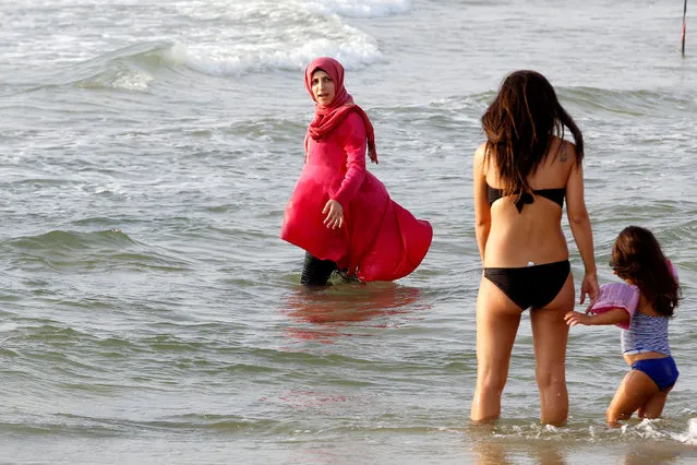 A Muslim woman wearing a Hijab stands in the Mediterranean Sea as an Israeli woman wearing a bikini stands nearby at a beach in Tel Aviv, Israel August 30, 2016. (Photo by Baz Ratner/Reuters)