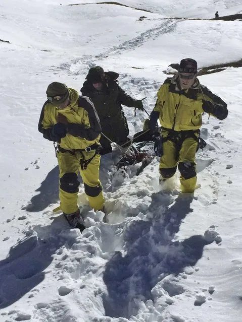 In this photo released by the Nepalese Army, rescue team members carry a victim of an avalanche before they airlift the body from Thorong La pass area, in Nepal, Thursday, October 16, 2014. Search teams in army helicopters rescued dozens of stranded foreign trekkers and recovered more bodies of victims of a blizzard and avalanches in the mountains of northern Nepal on Thursday. (Photo by AP Photo/The Nepalese Army)
