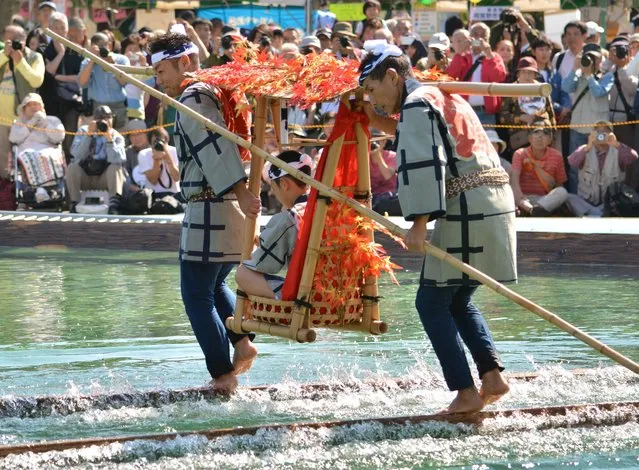 Raftsmen, members of the Kiba “kakunori” preservation society, perform a stunt on floating square timber logs at a local festival in Tokyo on October 19, 2014. The stunt was derived from lumberjacks daily work during the Edo period (1603-1868), when they made rafts with fire-hooks in their hands standing on floating logs. (Photo by Kazuhiro Nogi/AFP Photo)
