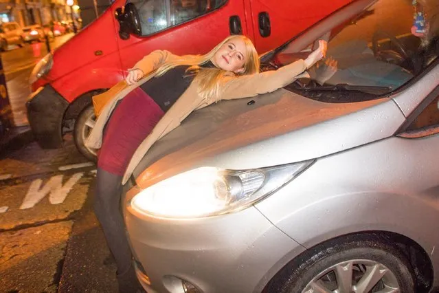 Revellers out and about in London, England on “Black Eye Friday” or “Mad Friday” on December 22, 2017. A young woman sprawls across the front of a car, enjoying the street party atmosphere. (Photo by London News Pictures)