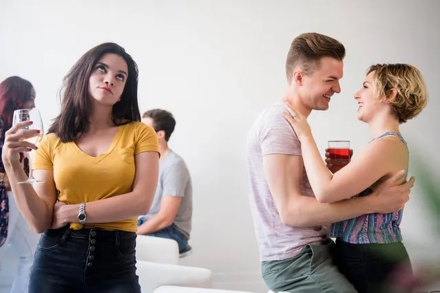 Woman at party rolling eyes at affectionate couple. (Photo by Jamie Grill/JGI/Getty Images)