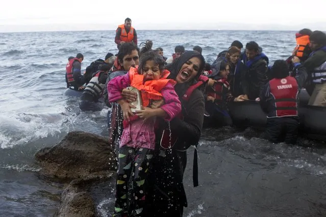 A migrant woman pulls a girl out of the water as refugees and migrants arrive on an overcrowded dinghy in rough sea on the Greek island of Lesbos, after crossing a part of the Aegean Sea from the Turkish coast, October 2, 2015. A record number of at least 430,000 refugees and migrants have taken rickety boats across the Mediterranean to Europe this year, 309,000 via Greece, according to International Organization for Migration figures. (Photo by Dimitris Michalakis/Reuters)