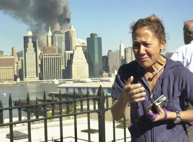 A woman reacts to a third explosion, possibly the collapse of the World Trade Center towers, while observing from the Brooklyn Promenade, which provides a view of the Manhattan skyline, Tuesday, September 11, 2001, in New York. (Photo by Kathy Willens/AP Photo)