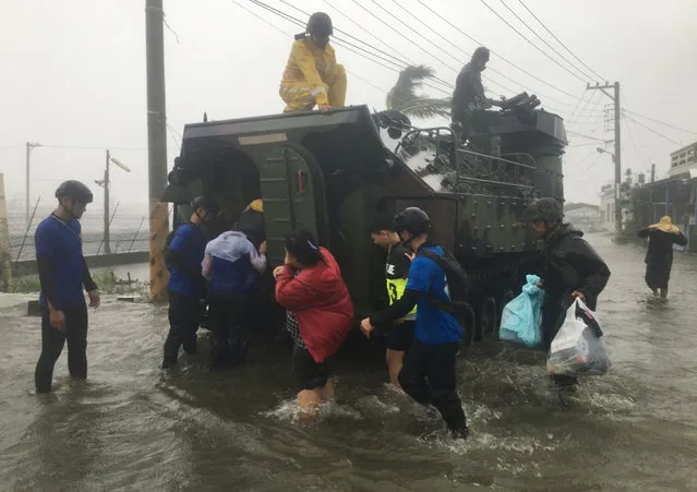 This photo by Taiwan agency CNA Photo shows residents affected by super typhoon Meranti being evacuated on a military armoured vehicle in southern Pingtung county on September 14, 2016. Parts of Taiwan were brought to a standstill September 14 as super typhoon Meranti skirted past the island's southern tip, bringing the strongest winds in 21 years and disrupting traffic ahead of a major holiday. (Photo by AFP Photo/Stringer)