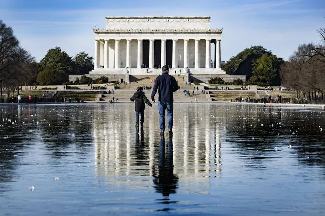 A man and a boy walk across the frozen Reflecting Pool towards the Lincoln Memorial on the National Mall in Washington, DC, on December 26, 2022. Heavy snow, howling winds, and air so frigid it instantly turned boiling water into ice took hold of much of the US over Christmas weekend, including normally temperate southern states. (Photo by Jim Watson/AFP Photo)