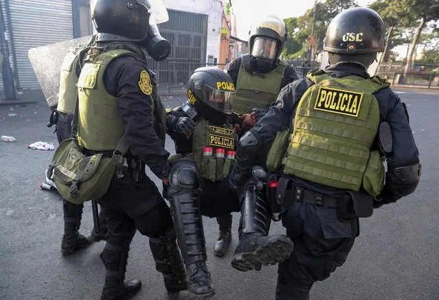 Police officers carry another officer during the “Take over Lima” march against Peru's President Dina Boluarte, following the ousting and arrest of former President Pedro Castillo, in Lima, Peru on January 19, 2023. (Photo by Sebastian Castaneda/Reuters)