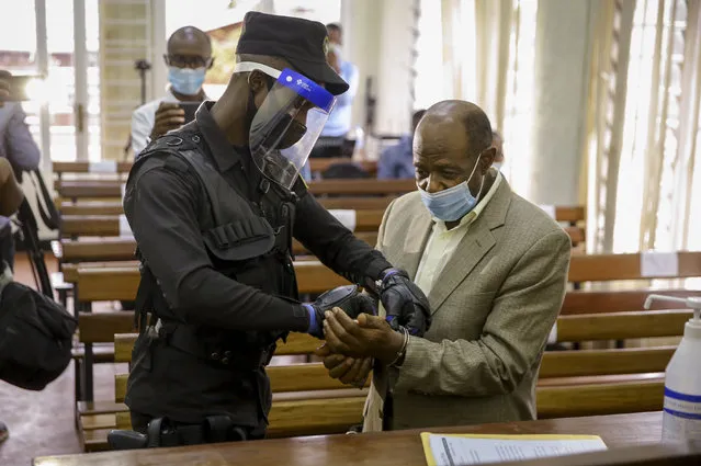 A policeman handcuffs Paul Rusesabagina, right, whose story inspired the film “Hotel Rwanda”, before leading him out of the Kicukiro Primary Court in the capital Kigali, Rwanda Monday, September 14, 2020. A Rwandan court on Monday charged Paul Rusesabagina with terrorism, complicity in murder, and forming an armed rebel group, while Rusesabagina declined to respond to all 13 charges, saying some did not qualify as criminal offenses and saying that he denied the accusations when he was questioned by Rwandan investigators. (Photo by Muhizi Olivier/AP Photo)