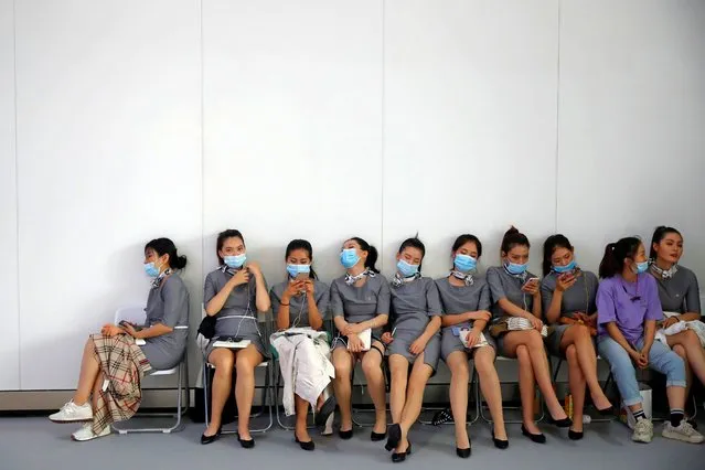Ushers wearing face masks following the coronavirus disease (COVID-19) outbreak, take a rest on the sidelines of the Beijing International Automotive Exhibition, or Auto China show, in Beijing, China on September 26, 2020. (Photo by Thomas Peter/Reuters)