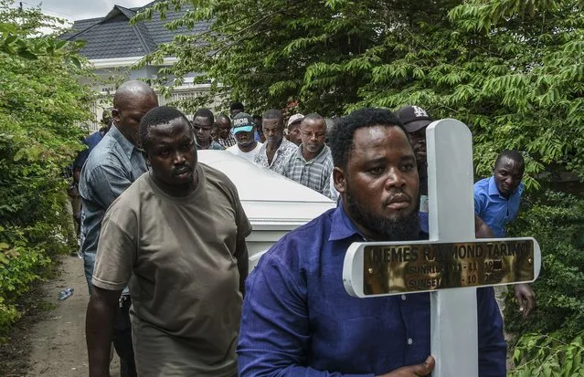 Mourners proceed bearing a cross and a coffin with the body of Tanzanian student, Nemes Tarimo, whose body arrived at his homeplace in Dar es Salaam, Tanzania, on January 27, 2023, after he was killed fighting for Russia in Ukraine after being recruited in jail. Nemes Tarimo was serving a seven-year term for an undisclosed offence when Russia's Wagner mercenary group recruited him for payment and the promise he would be freed after the war, Tanzanian authorities said this week. (Photo by Ericky Boniphace/AFP Photo)
