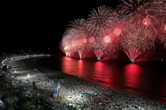 People gather to watch fireworks explode over Copacabana beach during New Year celebrations in Rio de Janeiro, Brazil on January 1, 2022. (Photo by Ricardo Moraes/Reuters)