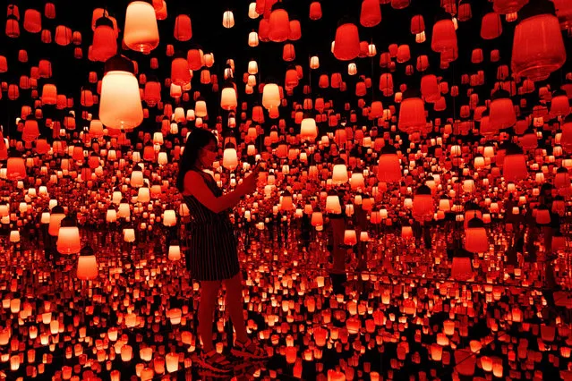 In this photo taken on October 14, 2020, a woman visits the “Forest of Lamps” digital installation room with hanging lamps which illuminate as visitors near them, in the TeamLab Borderless exhibition at Mori Building Digital Art Museum in Tokyo. (Photo by Behrouz Mehri/AFP Photo)