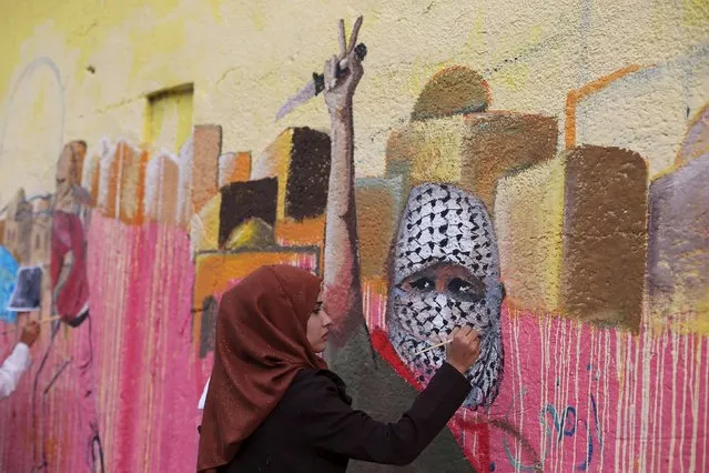 A Palestinian woman paints a mural, depicting a masked Palestinian holding a knife, in support of Palestinians committing stabbing attacks against Israelis, in Rafah in the southern Gaza Strip November 3, 2015. (Photo by Ibraheem Abu Mustafa/Reuters)