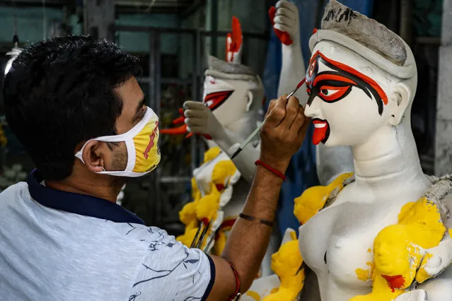 An artist wearing a face mask as a precautionary measure against the coronavirus paints a clay idol of Hindu goddess Kali inside his studio ahead of the Kali Puja festival in Kolkata, India, Friday, November 6, 2020. (Photo by Bikas Das/AP Photo)