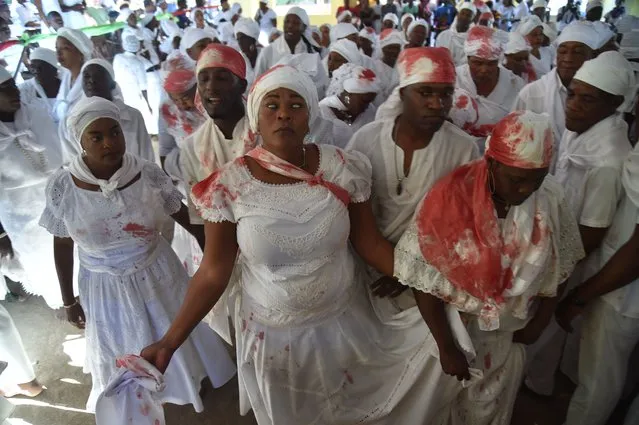 A Haitian voodoo follower wearing white clothes is seen in trance while participate in a voodoo ceremony in Souvenance, a suburb of Gonaives, 171km north of Port-au-Prince, on April 1, 2018. Haitian voodoo followers arrived in Souvenance to take part in the voodoo ceremonies held during Easter weekend. (Photo by Hector Retamal/AFP Photo)