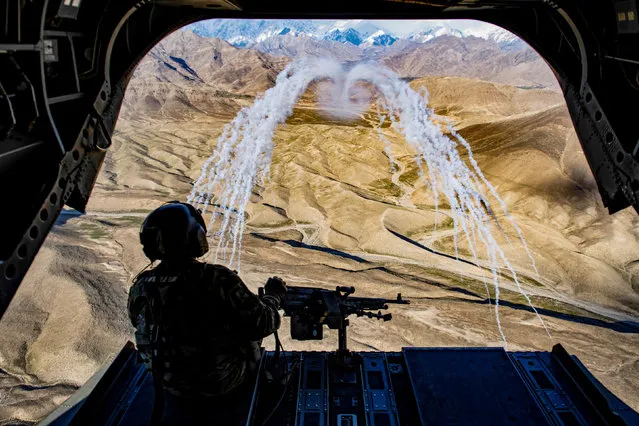 A U.S. Army crew chief flying on board a CH-47F Chinook helicopter observes the successful test of flares during a training flight in Afghanistan, March 14, 2018. (Photo by Tech. Sgt. Gregory Brook/Reuters/U.S. Air Force)