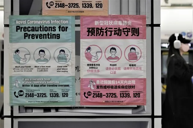 A woman wearing a face mask passes by posters reminding of precautions against the coronavirus at a subway station in Seoul, South Korea, Friday, February 10, 2023. South Korea says it will remove the entry restrictions it placed on short-term travelers from China since the start of the year as officials see the COVID-19 situation in that country as stabilizing. (Photo by Ahn Young-joon/AP Photo)