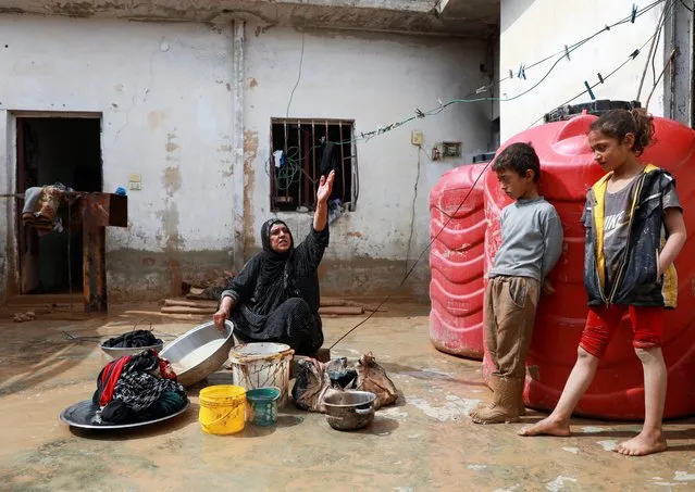 A woman gestures as she washes clothes at her house which was flooded due to heavy rainfall in Hasaka, Syria on March 18, 2023. (Photo by Orhan Qereman/Reuters)