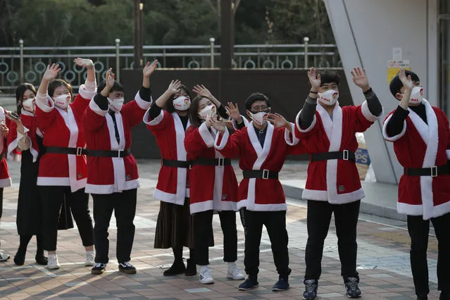 Volunteers wearing face masks wave after they load boxes onto a delivery truck during an event to send Christmas gifts for the underprivileged in Seoul, South Korea, Tuesday, December 22, 2020. The Korea Youth Foundation sent Christmas gifts using a courier to help prevent against the coronavirus as the social distancing measures. (Photo by Lee Jin-man/AP Photo)