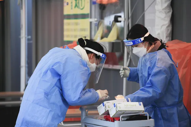 Medical workers wearing protective gear prepare for a coronavirus test at a coronavirus testing site in Seoul, South Korea, Sunday, December 27, 2020. (Photo by Park Min-suk/Newsis via AP Photo)