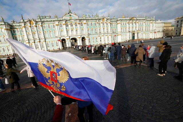People dance and wave a Russian national flag during National Unity Day celebrations as others (rear) queue to enter the Hermitage State Museum on Dvortsovaya (Palace) Square in St. Petersburg, Russia, 04 November 2025. The holiday commemorates the popular uprising led by Kuzma Minin and Prince Dmitry Pozharsky that ended the Polish-Lithuanian occupation of Moscow in 1612, ending the Time of Troubles. (Photo by Anatoly Maltsev/EPA)