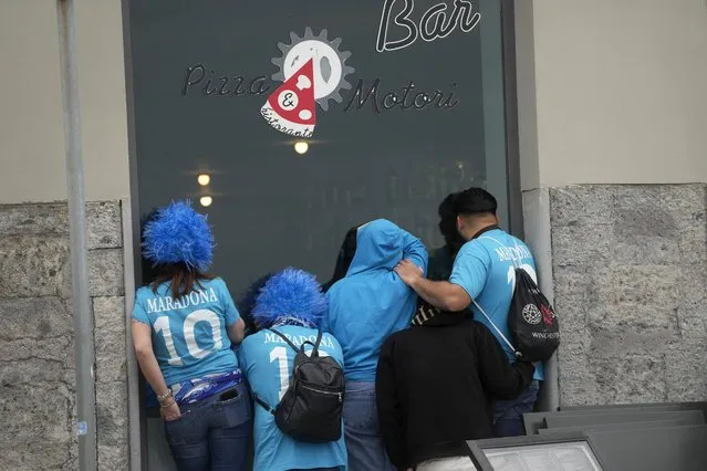 Napoli fans lean against the window of a Pizza restaurant to watch the Serie A soccer match between Napoli and Salernitana being played at the Diego Armando Maradona stadium, in Naples, Italy, Sunday, April 30, 2023. (Photo by Gregorio Borgia/AP Photo)