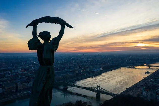 The sun rises behind the Liberty Statue on the top of Gellert Hill, a landmark of the Hungarian capital, in Budapest, Hungary, 2​7 December 2020. (Photo by Balazs Mohai/EPA/EFE)