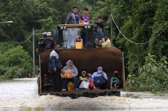 Residents ride a digger vehicle through floodwaters following heavy monsoon downpour in Lanchang, Malaysia's Pahang state on January 6, 2021. (Photo by Mohd Rasfan/AFP Photo)