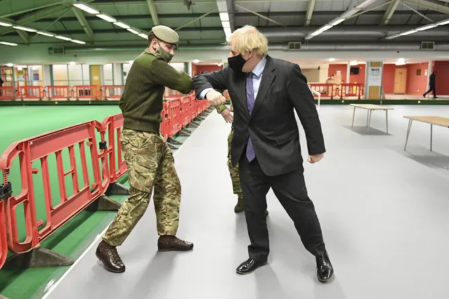 Britain's Prime Minister Boris Johnson elbow bumps a member of the military as he meets troops setting up a vaccination centre in the Castlemilk district of Glasgow, on his one day visit to Scotland, Thursday, January 28, 2021. Johnson is facing accusations that he is not abiding by lockdown rules as he makes a trip to Scotland on Thursday to laud the rapid rollout of coronavirus vaccines across the United Kingdom. (Photo by Jeff Mitchell/Pool Photo via AP Photo)