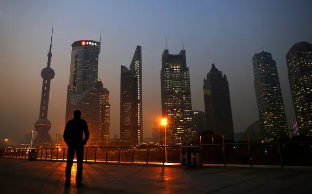 A man looks at the Pudong financial district of Shanghai in this November 20, 2013, file photo. China's annual consumer inflation hovered at a near five-year low of 1.5 percent in December, little changed from November's levels, signalling persistent weakness in the economy but giving policymakers more room to ease policy to support growth. (Photo by Carlos Barria/Reuters)