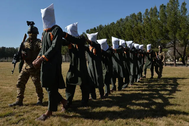 Afghan security forces escort suspected Taliban fighters as they are being presented in front of the media after an operation at the National Directorate of Security (NDS) headquarters in Herat on February 2, 2021. (Photo by Hoshang Hashimi/AFP Photo)