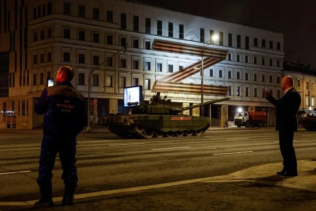 People take pictures as tanks drive along a road past a “Z” sign on a building, as they are relocated for a Victory Day parade preparation, to mark the 77th anniversary of the victory over Nazi Germany in World War Two, in Moscow, Russia, April 21, 2022. (Photo by Maxim Shemetov/Reuters)