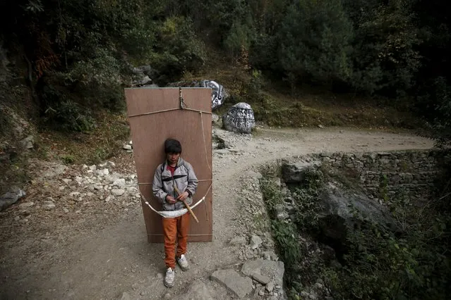 A porter takes a break as he carries plywood sheets used for building houses in Solukhumbu district, also known as the Everest region, in this picture taken November 28, 2015. (Photo by Navesh Chitrakar/Reuters)