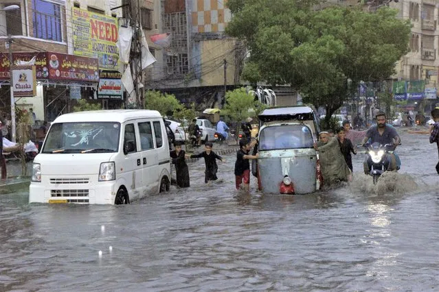 Motorcyclists and cars drive through a flooded road caused by heavy monsoon rainfall in Hyderabad, Pakistan, Sunday, July 23, 2023. (Photo by Pervez Masih/AP Photo)