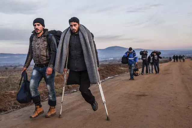 A man with one leg uses crutches as migrants and refugees walk on a road after crossing the Macedonian border into Serbia, near the village of Miratovac, on January 8, 2016. More than a million refugees and migrants arrived in Europe in 2015 in the worst crisis of its kind to face the continent since World War II. (Photo by Armend Nimani/AFP Photo)