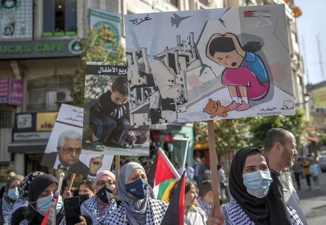 Palestinian women carry posters that read “no for terrorizing the children, Gaza, Palestine”, during a protest supporting the children in Gaza, in the West Bank city of Ramallah, Thursday, May 20, 2021. (Photo by Nasser Nasser/AP Photo)