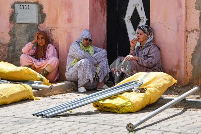 Women sit after receiving a shelter tent and relief aid at a distribution centre in the town of Amizmiz in al-Haouz province in the High Atlas mountains of central Morocco on September 12, 2023. (Photo by Fadel Senna/AFP Photo)