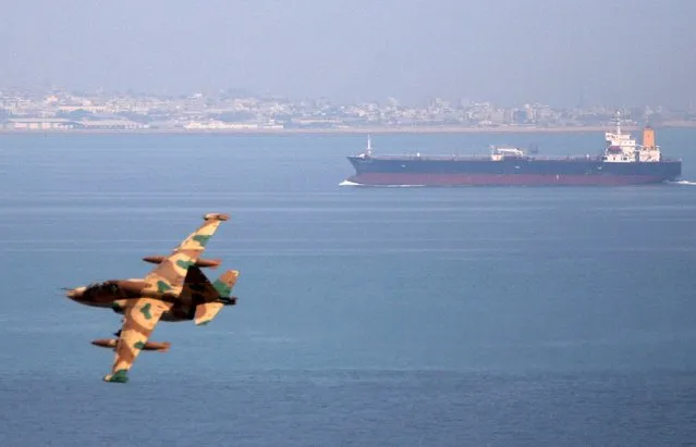 An Iranian military fighter plane flies past an oil tanker during naval manoeuvres in the Persian Gulf and Sea of Oman in this April 5, 2006 file photo. Iran plans to list its national tanker company to raise badly needed cash to upgrade its massive fleet and replace older vessels, as the middle east country prepares for an aggressive return to the global oil market. (Photo by Reuters/FARS News)