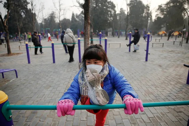 A woman wearing a face mask exercises in a park despite a red alert issued for air pollution in Beijing, China December 18, 2016. (Photo by Damir Sagolj/Reuters)