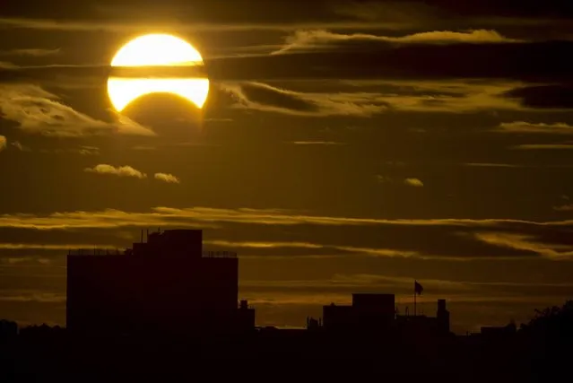 A partial Solar eclipse is seen just after sunrise over the Queens borough of New York across the East River on November 3, 2013 in New York. (Photo by Stan Honda/AFP Photo)