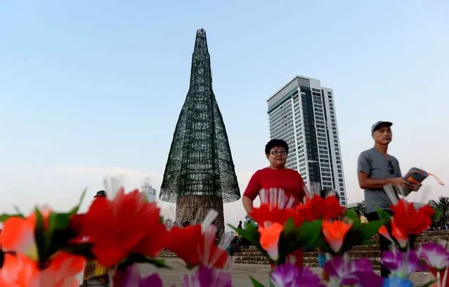 Sri Lankan pedestrians walk past a partially- constructed Christmas tree in Colombo on December 24, 2016 Sri Lanka surpassed the world record for the tallest artificial Christmas tree on December 24 despite building delays forcing organisers to prune the structure by almost half, an official said. (Photo by Lakruwan Wanniarachchi/AFP Photo)