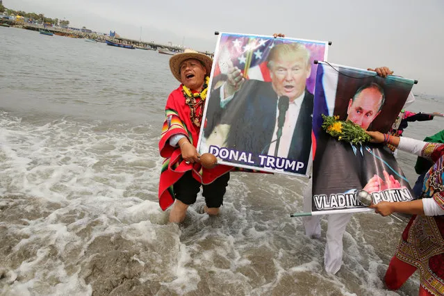 Peruvian shamans holding a poster of U.S. President-elect Donald Trump and Russian President Vladimir Putin perform a ritual of predictions for the new year at Pescadores beach in Chorrillos, Lima, Peru, December 29, 2016. (Photo by Mariana Bazo/Reuters)