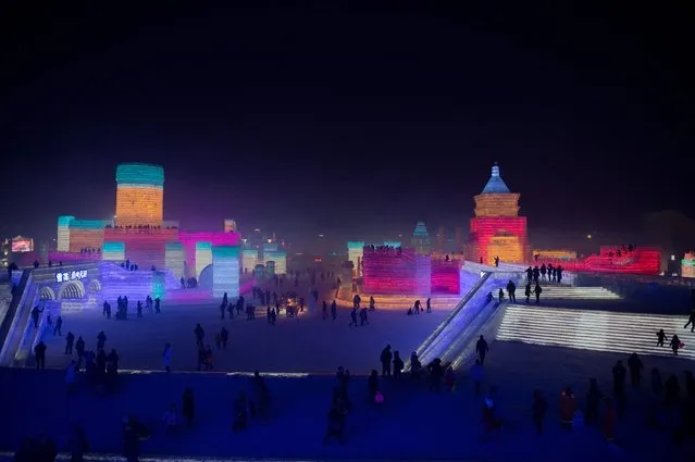 People visit ice sculptures illuminated by coloured lights marking the opening of the Harbin Ice and Snow Festival to celebrate the new year in Harbin on January 5, 2017. (Photo by Nicolas Asfouri/AFP Photo)