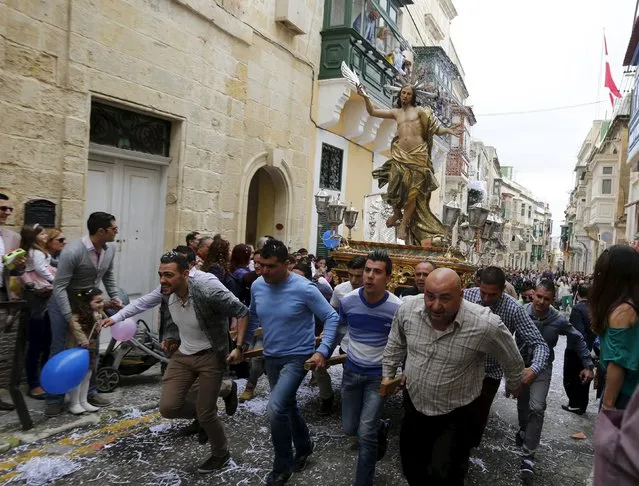 Worshippers run while carrying a statue of the Risen Christ as confetti streams down during an Easter Sunday procession in Cospicua, outside Valletta April 5, 2015. (Photo by Darrin Zammit Lupi/Reuters)