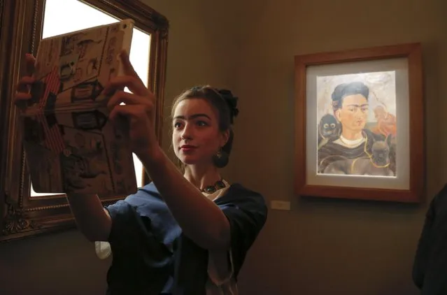 A visitor stylised as Frida Kahlo takes a selfie with Frida's Kahlo self-portrait at the Frida Kahlo exhibition in St.Petersburg, Russia, Tuesday, February 2, 2016. (Photo by Dmitry Lovetsky/AP Photo)