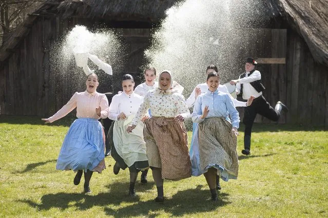 Dressed in folk costumes young women run away because young men pour water from their buckets on them as members of Nyirseg Dance Group perform Easter folk traditions in the Museum Village in Nyiregyhaza, 227 kms northeast of Budapest, Hungary, Monday, April 6, 2015. (Photo by Attila Balazs/AP Photo/MTI)