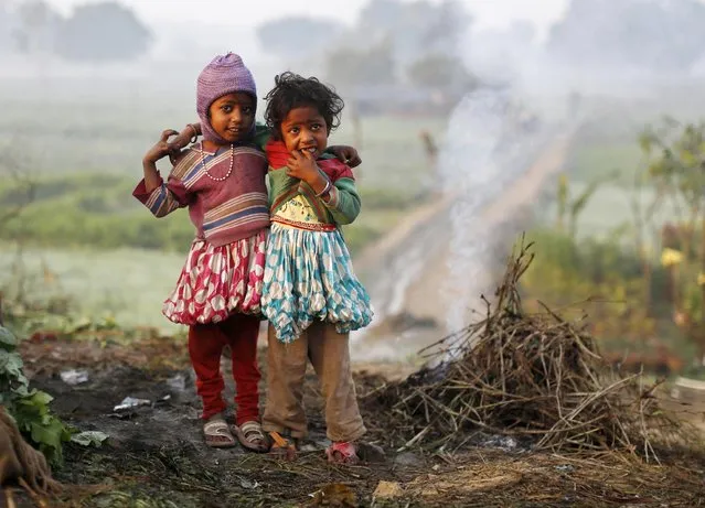 Girls look on as they stand near smoke from twigs which were set on fire by their parents to warm themselves at a vegetable field in New Delhi early December 11, 2013. (Photo by Ahmad Masood/Reuters)