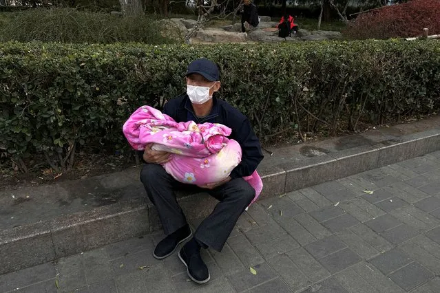 A man carrying a child sits outside a children's hospital in Beijing, China on November 27, 2023. (Photo by Tingshu Wang/Reuters)