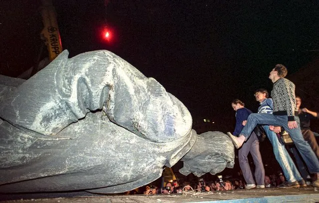 In this Friday, August 23, 1991 file photo, people kick the head of the statue of Felix Dzerzhinsky, the founder of the Soviet secret police, in front of the KGB main headquarters on the Lubyanka Square. (Photo by Alexander Zemlianichenko/AP Photo/File)