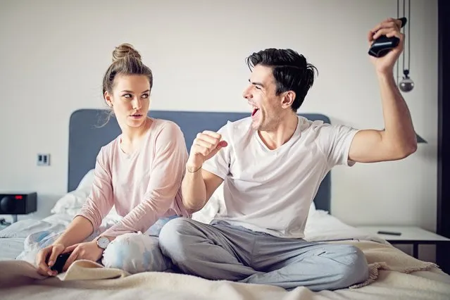 Happy couple is playing video games in bed. (Photo by praetorianphoto/Getty Images)