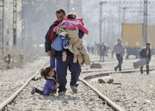 A child falls while walking with a man on the railway tracks near the border between Greece and Macedonia in the northern Greek border station of Idomeni, Thursday, March 3, 2016. Thousands of refugees and migrants wait on the border between Greece and Macedonia and about 30,000 refugees and other migrants are stranded in Greece, with 10,000 at the Idomeni border crossing to Macedonia. (Photo by Vadim Ghirda/AP Photo)